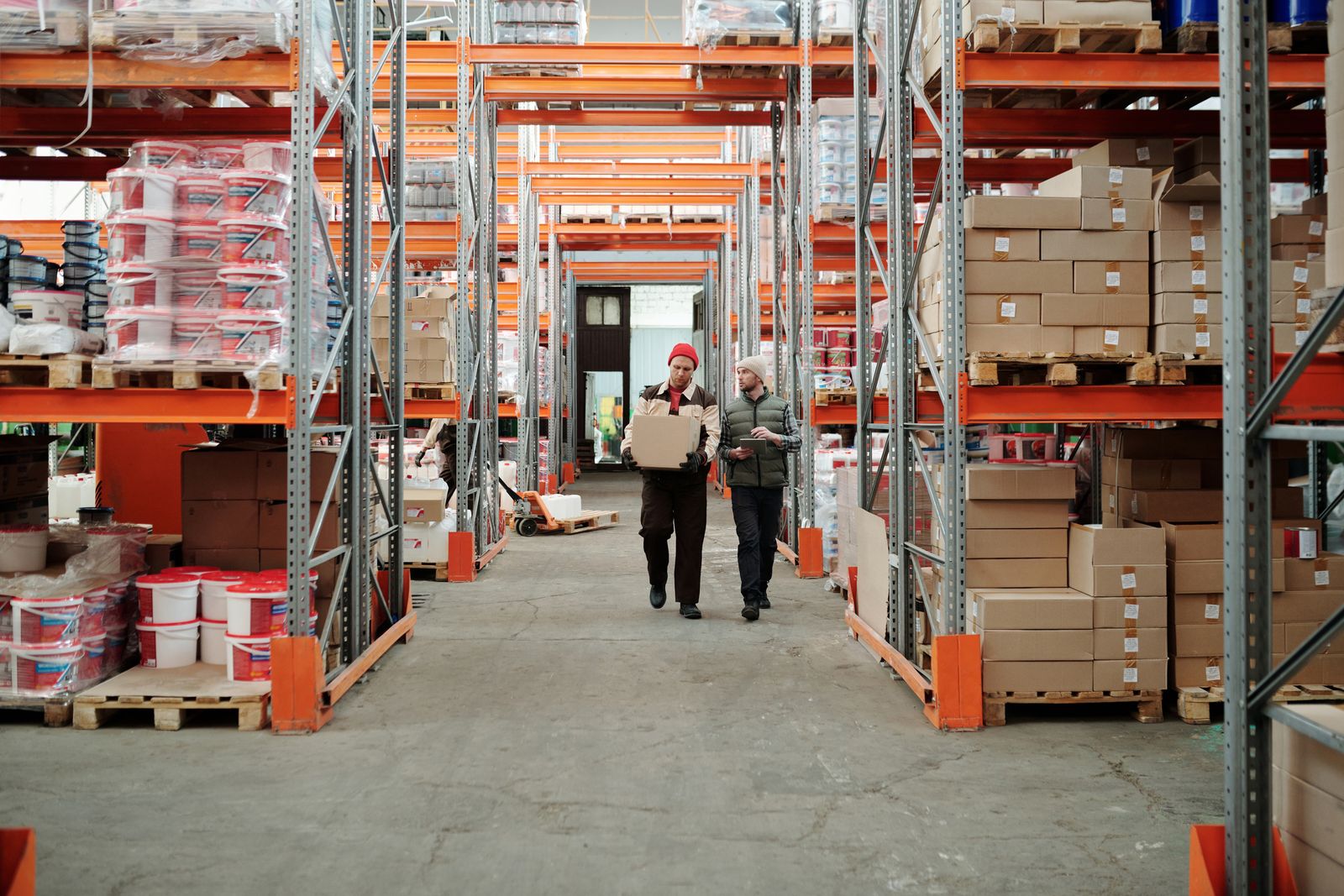 Warehouse team moving goods between stocked pallet racks